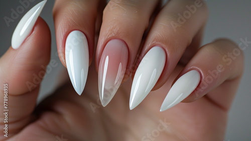 Elegant female hand with long white stiletto manicured nails on a white background with soft feather texture.