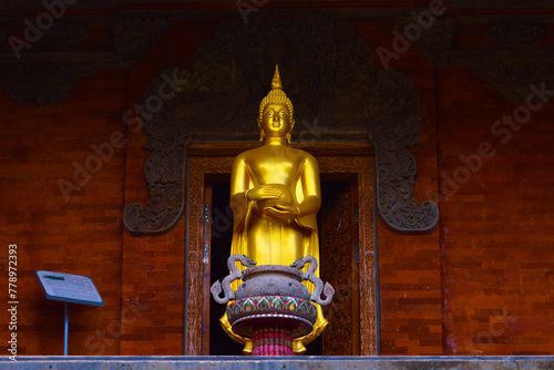 Low Angle View Of Golden Buddha Statue Standing While Holding A Pitcher In Front Of A Room Of Buddhist Temple photo