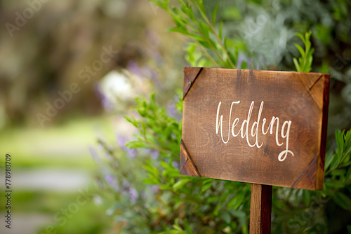 Wooden board with the inscription in paint Wedding. Sign for guests at the entrance, outdoors wedding ceremony decoration. Hand made signboard, welcome wedding wooden plaque with garden on background © Magryt