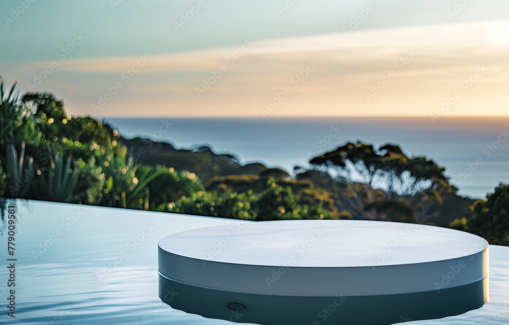 A closeup shot of an elegant white circular table with rounded edges placed near a pool, overlooking nature and the sea at sunset in front of the Australian cliffside. For product display montage.