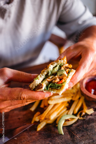 Male hands holding delicious tuna sandwich and salad close-up. Delicious food concept