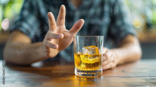 Man with whiskey signaling peace sign - An adult male casually displays a peace sign with his fingers while enjoying a whiskey in a relaxed bar setting, suggesting a carefree attitude photo