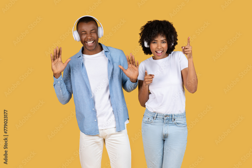 Couple with headphones and dancing gestures on yellow Couple with headphones and dancing gestures on yellow