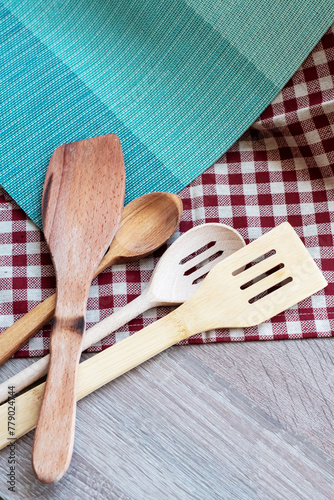 four household items, wooden kitchen utensils on red and white tablecloth, place for text and logo