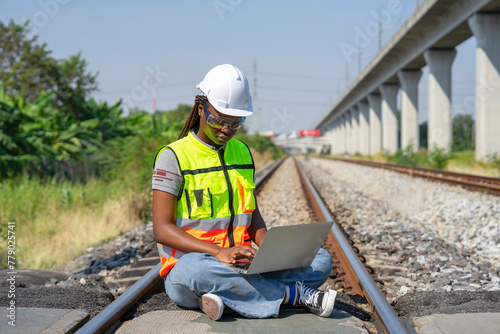 young african female engineer working on laptop to check railway tracks for maintenance at railroad,concept of safety quality control,rail transport,transportation industry