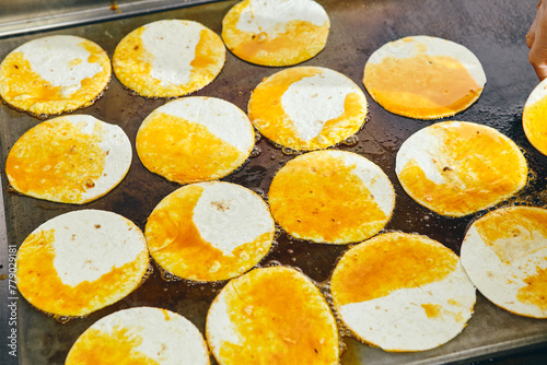 Tacos tortillas preparation on griddle in professional kitchen in restaurant.