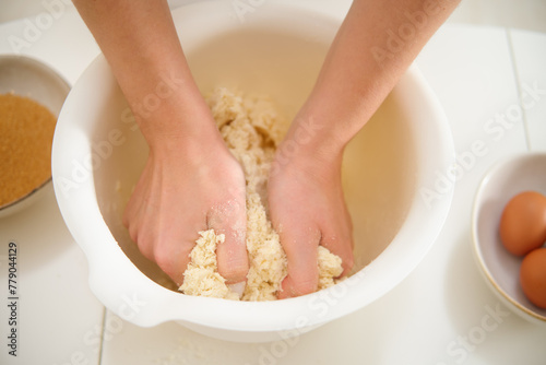 Female hands making dough in a bowl with flour on a white background. Process of cooking pecan pie in home kitchen for American Thanksgiving Day.