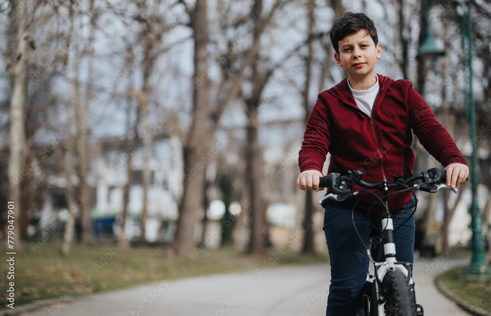 A boy experiences the joy and freedom of cycling alone on a path surrounded by the greenery of a city park.