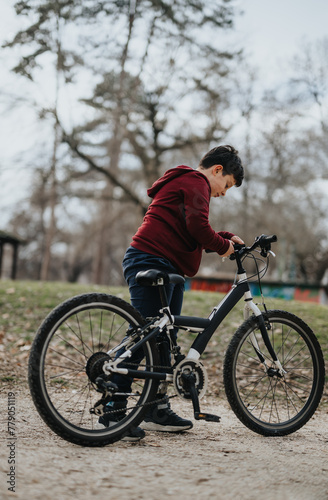 Active young adult examining his mountain bike before riding in an outdoor park setting with trees in the background.