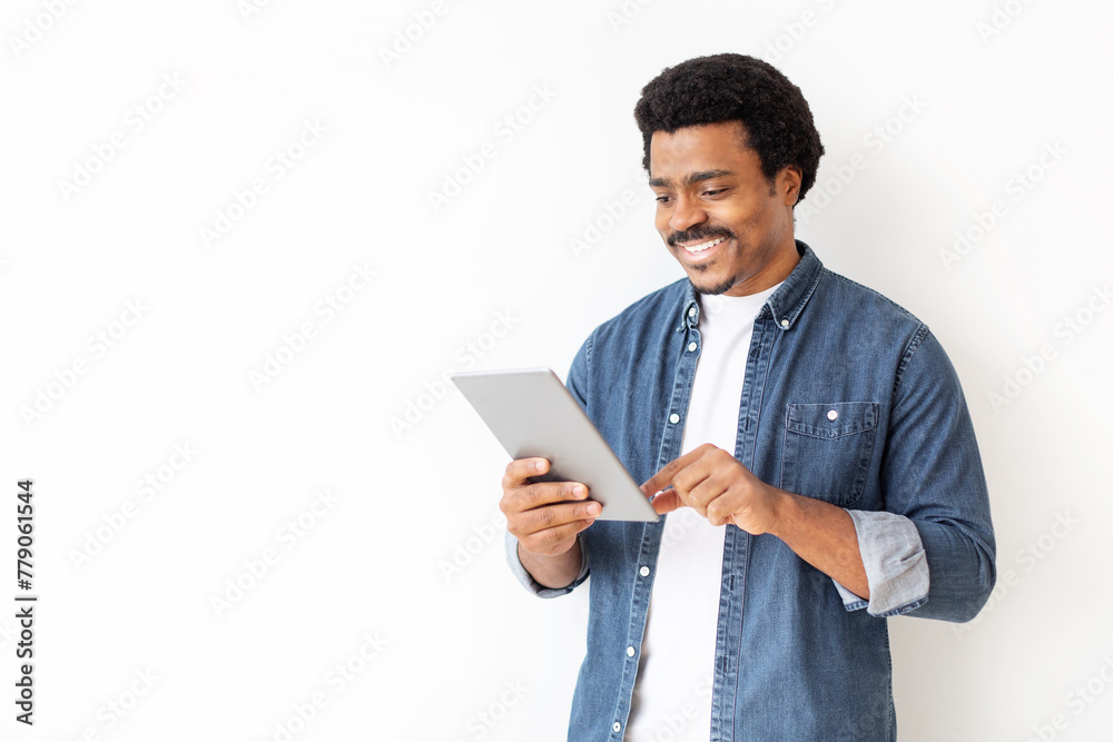 Content black man in denim shirt engaging with digital tablet Content black man in denim shirt engaging with digital tablet