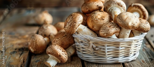A white basket brimming with fresh brown mushrooms sits atop a sturdy wooden table.