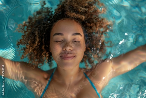 A woman with curly hair is floating in a pool, smiling and looking relaxed © top images