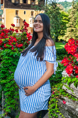 Smiling beautiful pregnant South American girl wearing a long striped shirt