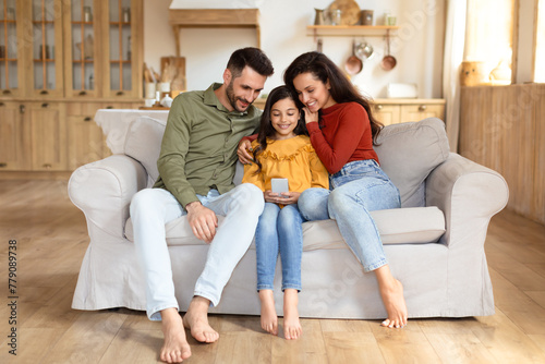 Family viewing phone together on couch at home