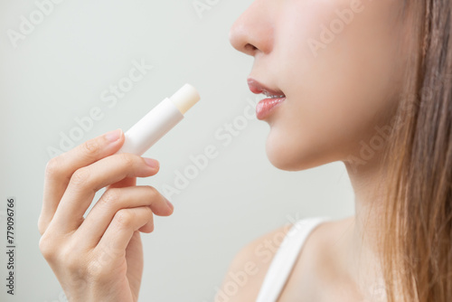 Lip care protection concept  pretty asian young woman  girl hand applying lipstick balm with moisturising on dry mouth from natural beauty product  skincare routine  makeup and cosmetics on background