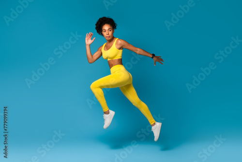 Athlete captured mid-air in yellow sportswear on blue background