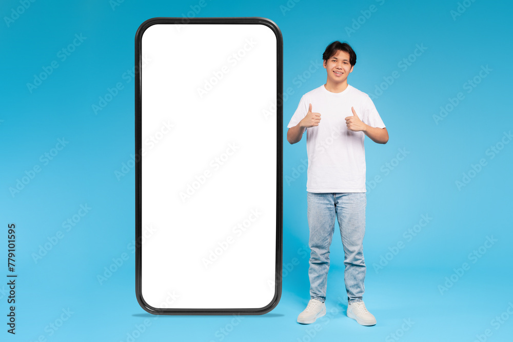 Young guy and gigantic smartphone mockup, blue background Young guy and gigantic smartphone mockup, blue background