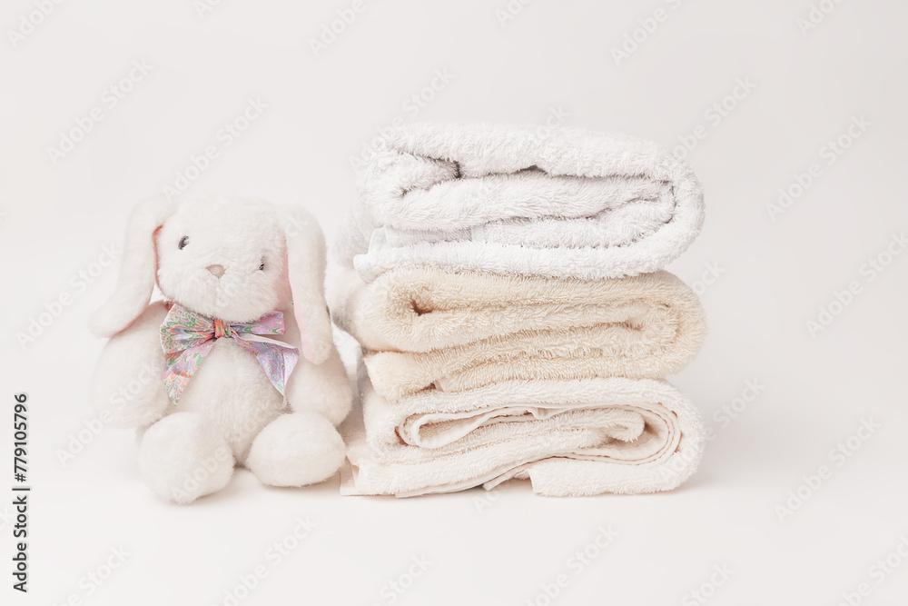 Bunny fluffy toy with clean baby beige soft bath towels stack on a white background Bunny fluffy toy with clean baby beige soft bath towels stack on a white background