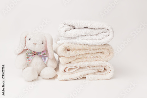 Bunny fluffy toy with clean baby beige soft bath towels stack on a white background © Min Wan