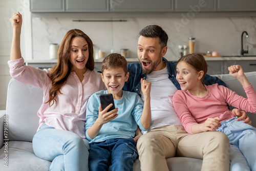 Family celebrating success with smartphone at home