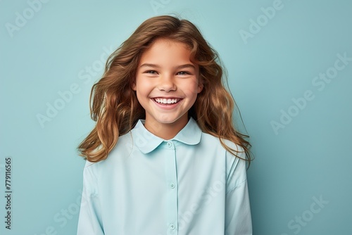 A young girl with long hair is smiling and wearing a blue shirt photo