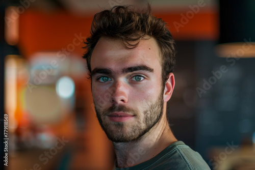 A man with a beard and green eyes looks at the camera