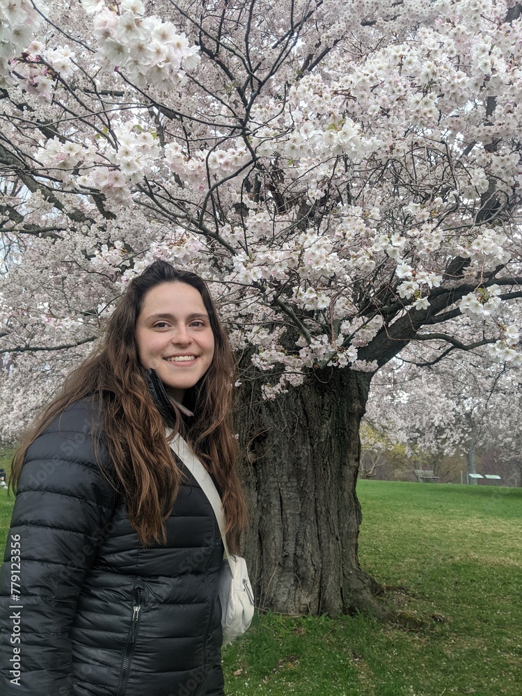 A portrait of a woman in front of beautiful cherry blossom trees while they bloom in the spring A portrait of a woman in front of beautiful cherry blossom trees while they bloom in the spring