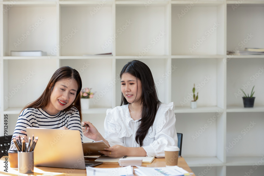 Two cheerful businesswomen brainstorming and sharing ideas in a collaborative workspace, with a laptop and coffee on the table. Two cheerful businesswomen brainstorming and sharing ideas in a collaborative workspace, with a laptop and coffee on the table.