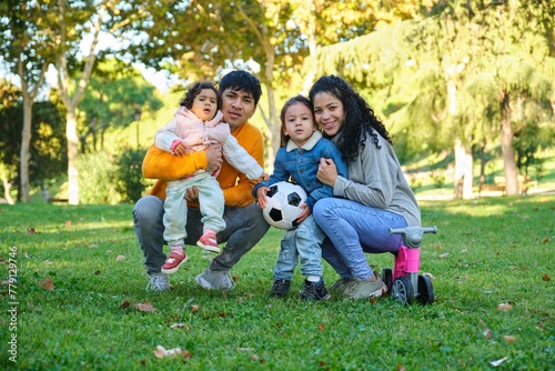 Hispanic family with two children soccer ball and balance bike in a park. Latin family.