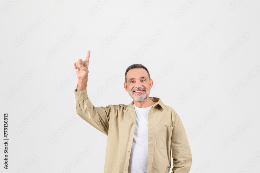 Senior man joyfully pointing upwards at copy space Senior man joyfully pointing upwards at copy space
