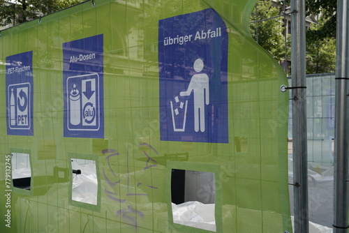 Improvised separation of waste at city festival in Zurich, Switzerland. There are openings with pictograms and inscriptions in German to throw PET plastic bottles, Alu cans and other waste.   photo