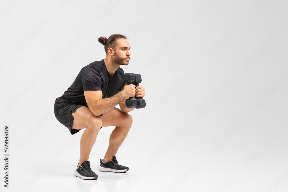 Man crouching with dumbbells in workout pose Man crouching with dumbbells in workout pose