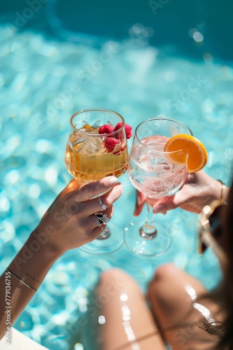 Women clinking glasses with cocktails at poolside