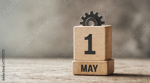 Wooden calendar block with metallic gear and May 1 date against concrete wall as symbol of International Workers', Labour, Labor Day celebration