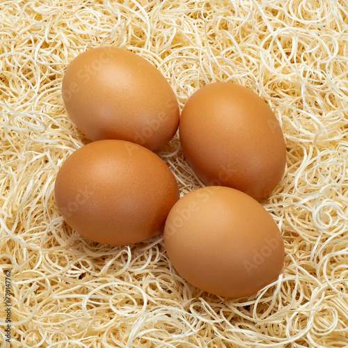 Close up image of four eggs on a bed of straw. The straw is white and the eggs are clean and unmarked.