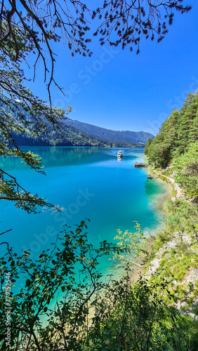 Panoramic view of alpine landscape seen from east bank of lake Weissensee in Carinthia, Austria. Tranquil forest in serene landscape amidst remote untouched nature in summer. Pristine turquoise water © Chris