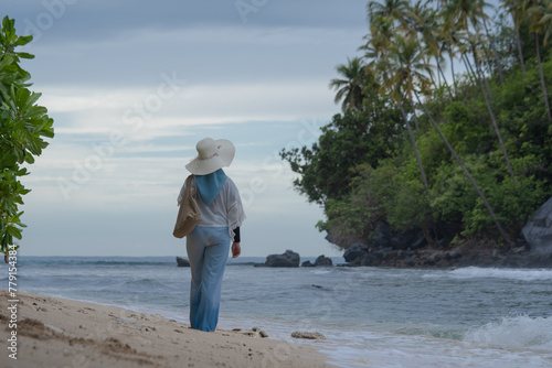 Fototapeta Naklejka Na Ścianę i Meble -  A woman walks alone on a beautiful beach