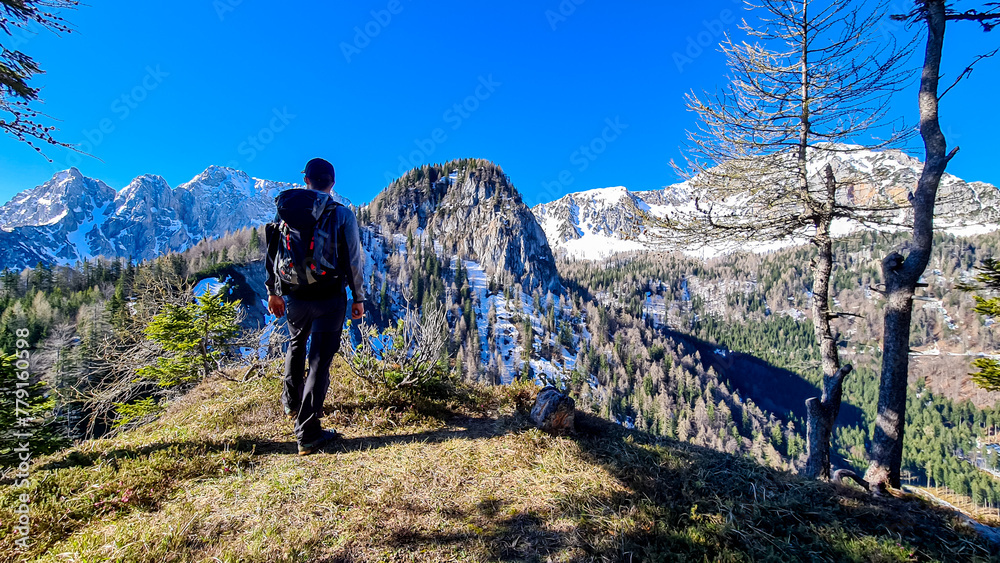 Hiker man enjoying scenic view of Karawanks mountain range in Carinthia, Austria. Looking at snow capped summit of Vertatscha and Hochstuhl. Remote alpine landscape in Bodental, Austrian Alps