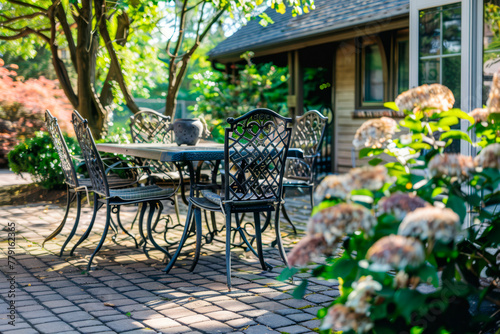 Cozy vintage backyard full of beautiful flowers. Chairs and table arranged in patio outside house.