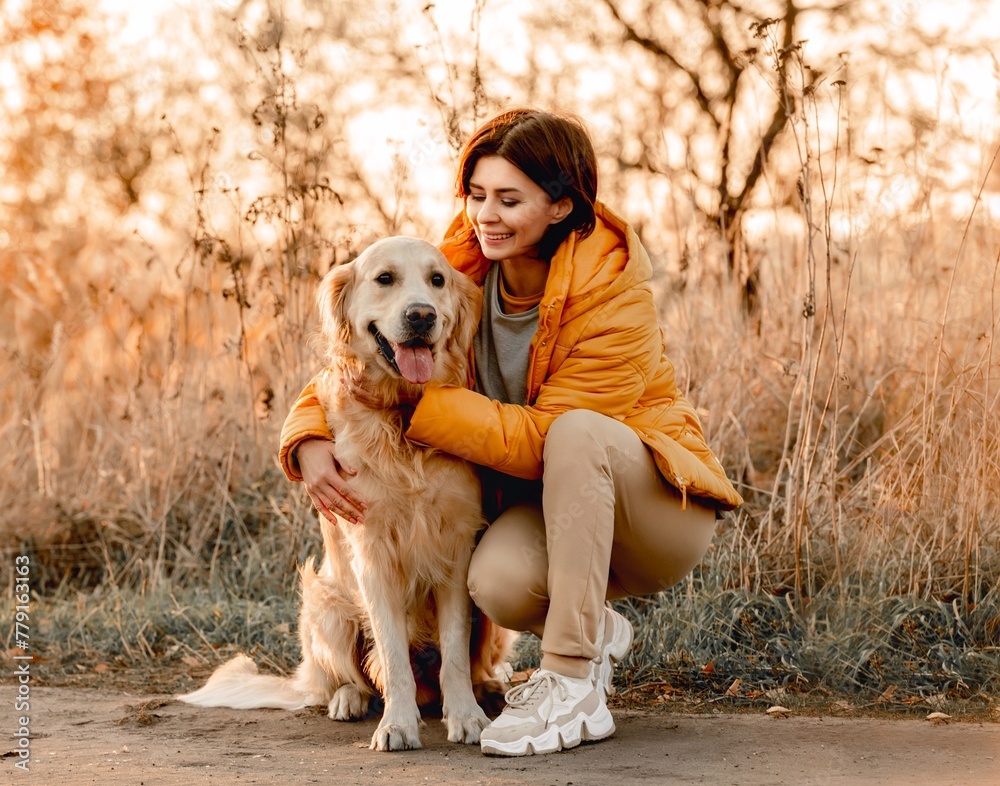 Girl hugging golden retriever dog with sunset light outdoors. Young woman petting doggy pet labrador at nature at autumn Girl hugging golden retriever dog with sunset light outdoors. Young woman petting doggy pet labrador at nature at autumn