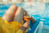 Woman with wine relaxing by the swimming pool.