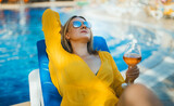 Pretty woman with wine relaxing by the pool.