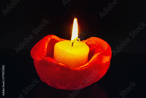 Close up of single burning candle light on black background