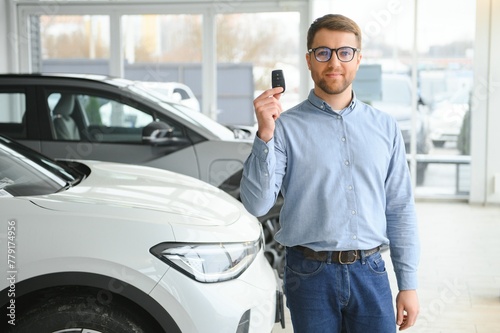 A happy man chooses a new electric car at a car dealership. The concept of buying an ecological car © Serhii