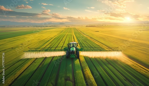 A tractor spraying pillar liquid on the vast green fields at sunset  with a wideangle aerial view of farmland in midsummer. 
