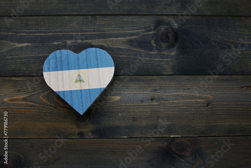 wooden heart with national flag of nicaragua on the wooden background.