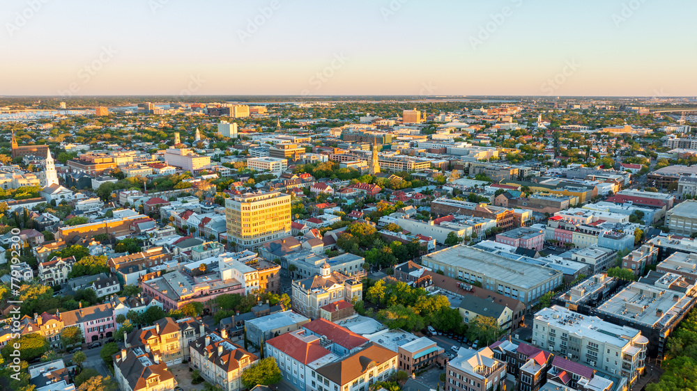 Obraz premium Golden sunrise light bathes downtown Charleston, South Carolina, with historic buildings and streets visible from an aerial view.