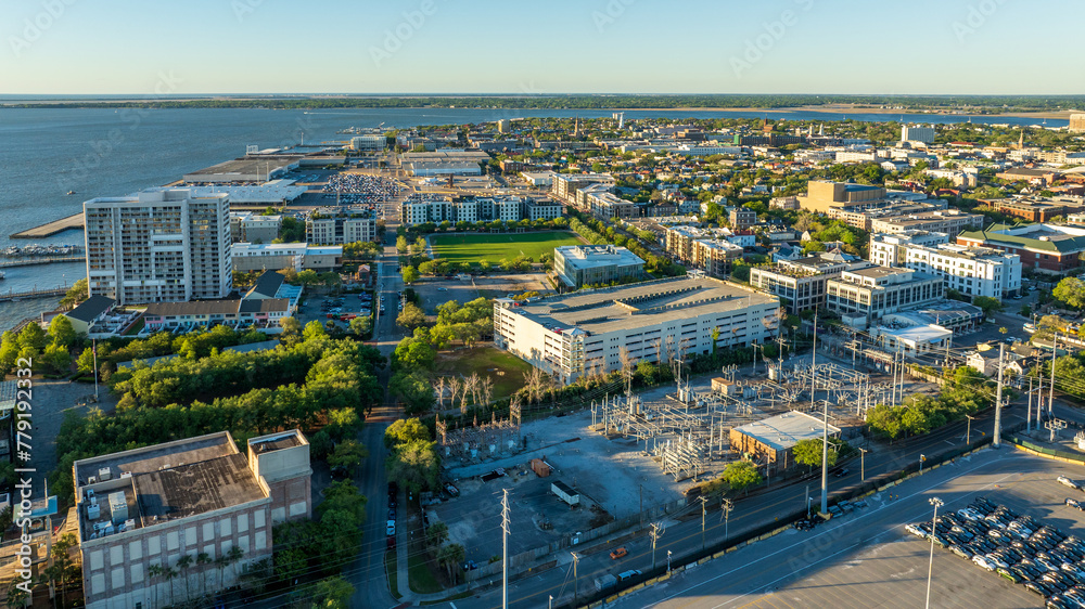 Obraz premium Golden sunrise light bathes downtown Charleston, South Carolina, with historic buildings and streets visible from an aerial view.