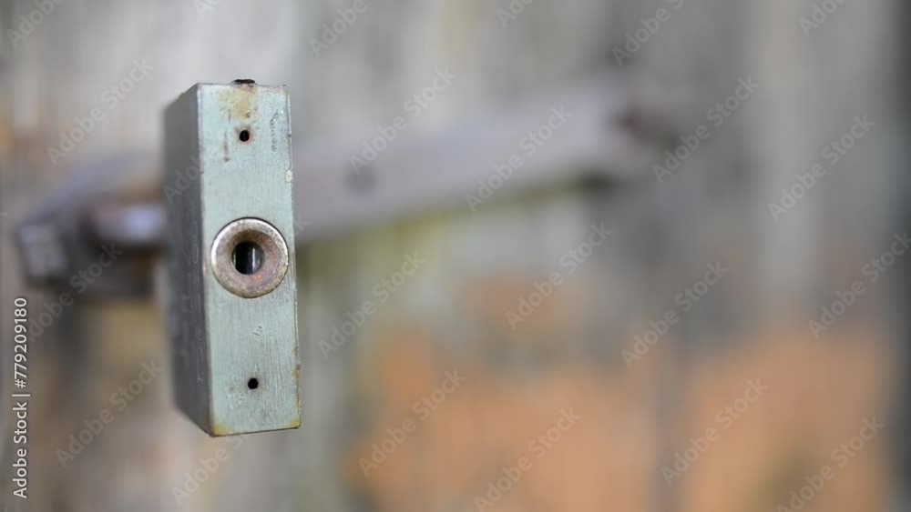 Old metal lock swinging on a rusty hinge on a dilapidated wooden shed. Old metal lock swinging on a rusty hinge on a dilapidated wooden shed.