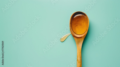 Wood spoon dripping honey isolated on a blue background with empty space around it, in a closeup shot. Concept for healthy eating and menu design concepts photo